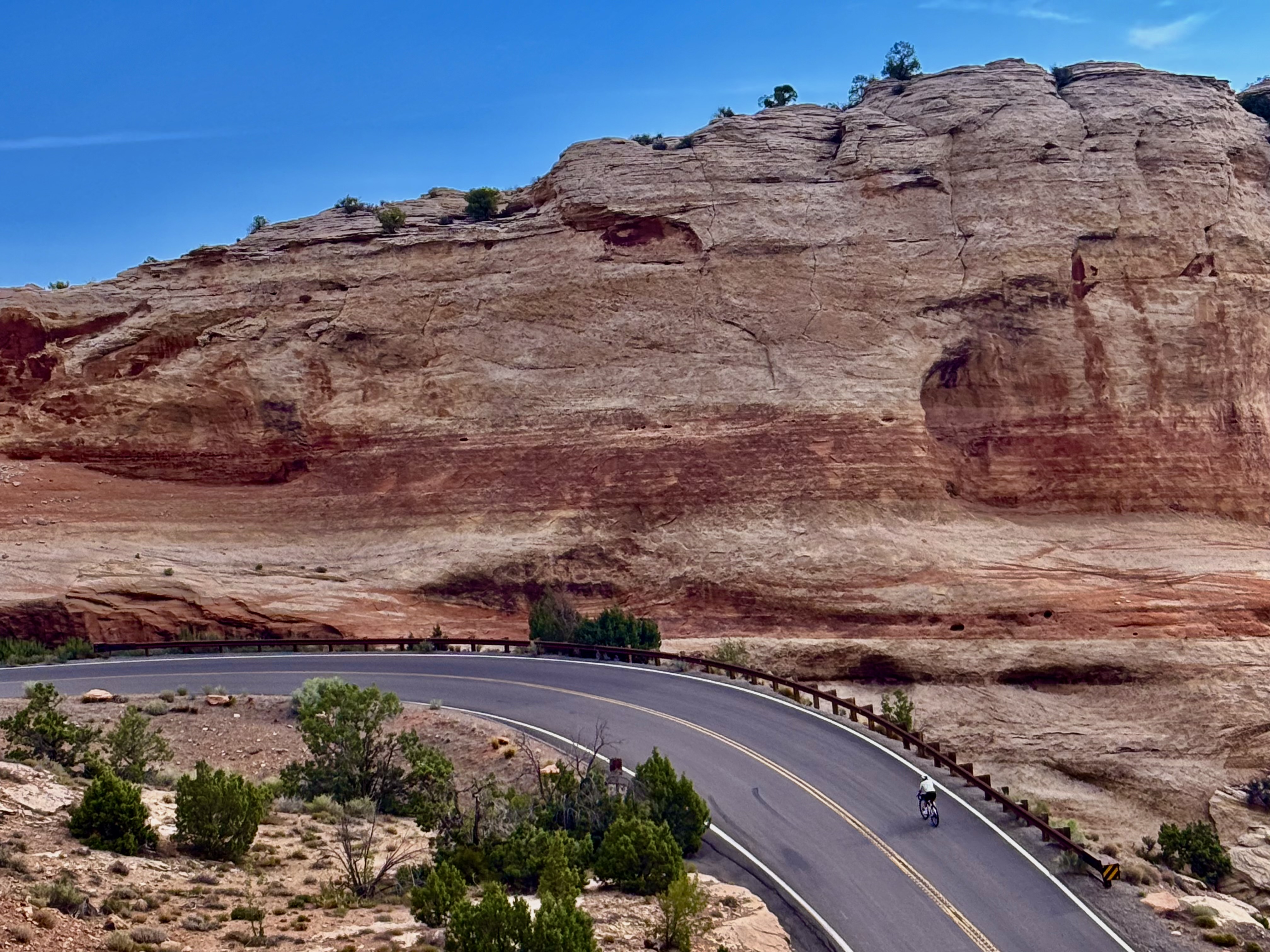 Cyclist riding up steep slope at Colorado National Monument Rim Rock Drive